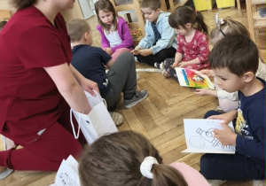 Rodzic wręcza dzieciom kolorowanki