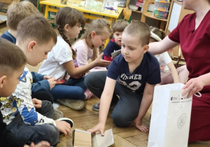 Rodzic wręcza dzieciom kolorowanki