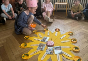 Dziewczynka rozkłada koraliki na słoneczku urodzinowym.