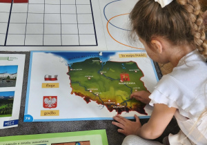 Na zdjęciu widzimy dziewczynkę, która wskazuje na ilustracji najdłuższą rzekę Polski - Wisłę.