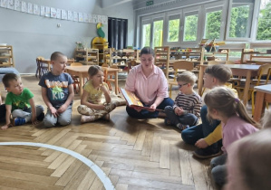 Na zdjęciu widzimy mamę Viktora, która czyta dzieciom książkę.