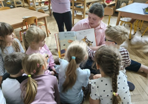 Na zdjęciu widzimy dzieci, które oglądają ilustracje z książki.