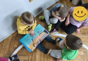 Na zdjęciu widzimy grupkę dzieci, które oglądają książkę przeczytaną przez mamę Viktora.