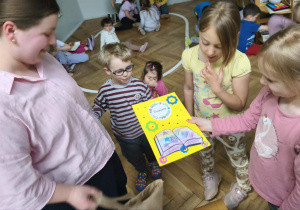 Na zdjęciu widzimy dziewczynki, które wręczają mamie Viktora podziękowanie za zaangażowanie w akcję "Głośnego Czytania" w grupie.