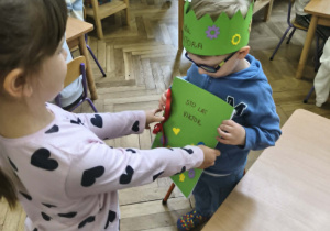 Na zdjęciu widzimy dziewczynkę, która daje Jubilatowi prezent od dzieci w postaci książeczki z laurkami.