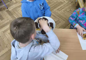 Na zdjęciu widzimy Jubilata, który częstuje dzieci babeczkami.