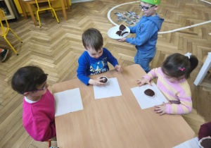 Na zdjęciu widzimy Jubilata, który częstuje dzieci babeczkami.