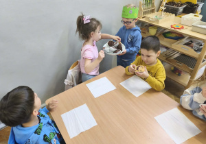 Na zdjęciu widzimy Jubilata, który częstuje dzieci babeczkami.