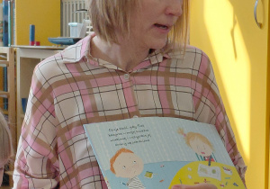 Mama Helenki czyta dzieciom książeczkę.