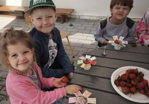 Dzieci jedzą lody z truskawkami