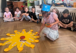Na zdjęciu dziewczynka rozkłada koraliki na talerzykach.