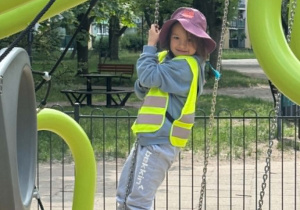 Zdjęcie przedstawia dziewczynkę na oponach na placu zabaw.