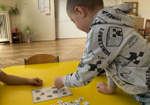 Zdjęcie przedstawia chłopca układającego obrazki na planszy.