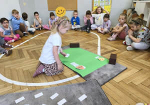 Na zdjęciu widzimy dziewczynkę, która przyporządkowuje kartkę ze zdaniem do odpowiedniego znaczka.