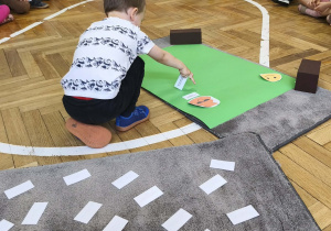 Na zdjęciu widzimy chłopca, który przyporządkowuje kartkę ze zdaniem do odpowiedniego znaczka.