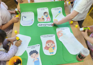 Na zdjęciu widzimy grupkę dzieci, które tworzą plakat "Czystość to zdrowie".