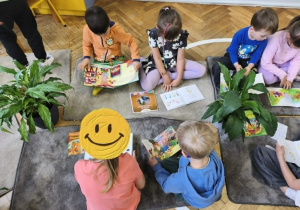 Na zdjęciu widzimy dzieci, które oglądają książki.