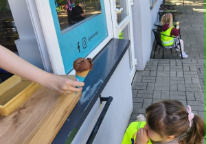 Na zdjęciu widzimy dziewczynkę, która otrzymuje loda.
