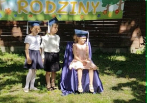 Na zdjęciu dziewczynka w birecie siedzi na tronie.