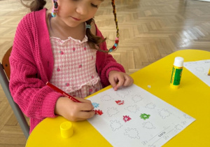 Na zdjęciu dziewczynka koloruje wskazany element pracy.