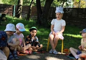 jubilatka siedząca na krześle a wokół niej zebrane dzieci w kręgu