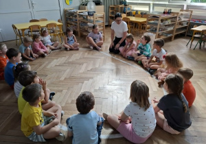 grupa dzieci i kobieta siedzą na elipsie