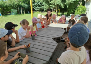 dzieci i kobieta siedzą przy stołach na tarasie