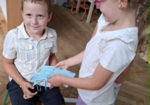 dziewczynka wręcza chłopcu książeczkę z laurek