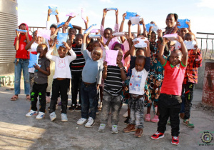 Zdjęcie przedstawia się grupę kenińskich dzieci, które się cieszą z powodu upominków.