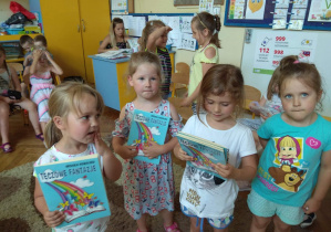 Na zdjęciu jest grupa dziewczynek, które w ręku trzymają książeczkę podarowaną przez poetkę pt. " Tęczowe fantazje"