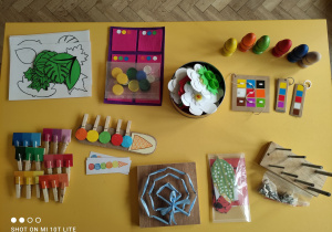 Zdjęcie przedstawia pomoce rozwojowe montessori leżące na żółtym stoliku.
