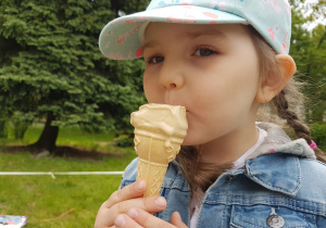 Zdjęcie przedstawia dziewczynkę jedzącą lody.