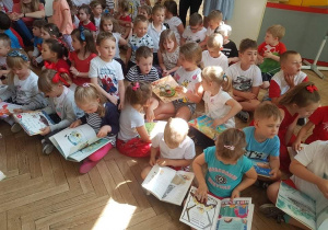 na zdjęciu widać dużą grupę dzieci oglądających książki