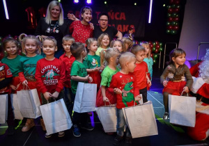 Zdjęcie przedstawia wolontariuszkę, nauczycielki i dzieci po występie na świątecznej scenie.