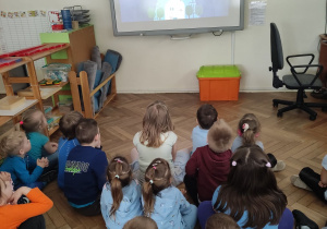 Zdjęcie przedstawia dzieci oglądające film edukacyjny na tablicy interaktywnej.