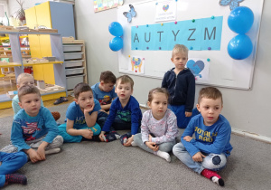 Zdjęcie przedstawia dzieci ubrane na niebiesko biorące udział w zajęciach.