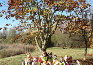 Na zdjęciu widać grupę dzieci, które odnalazły drzewo przedstawione na zdjęciu