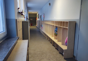 korytarz z szatnią dla dzieci, szare ściany, szafki idnywidualne dla dzieci w kolorze janego brązu