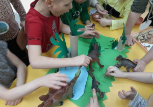 Zdjęcie przedstawia grupę dzieci z dinozaurami